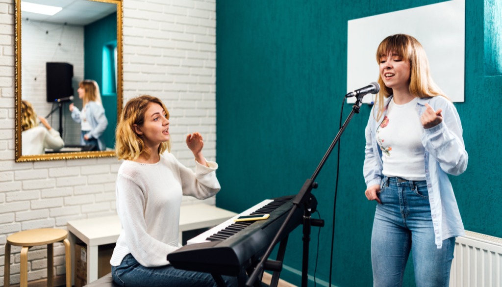 A young girl singing in a studio with her vocal coach