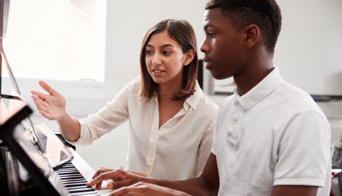 Piano teacher sitting with student going over a lesson